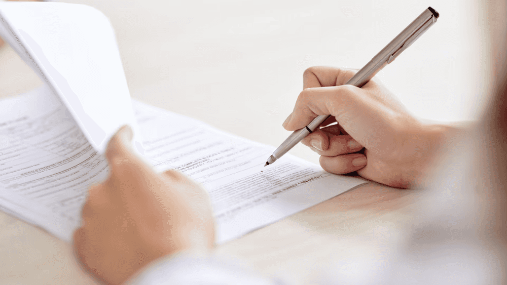 Person signing paperwork to buy a used car from Whitten Brothers Automotive, a top used car dealership in Richmond, VA