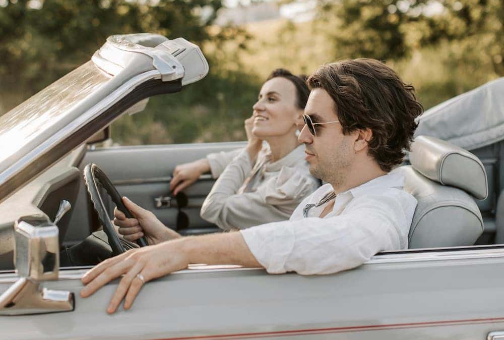 A man and woman driving in one of the best road trip cars