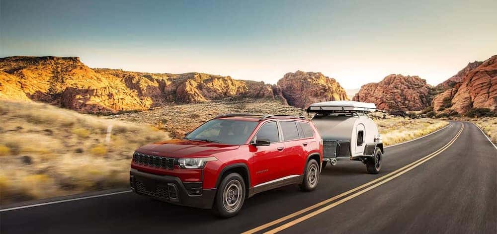 Red 2026 Jeep Cherokee towing a small trailer. 2026 Jeep Cherokee towing capacity display.