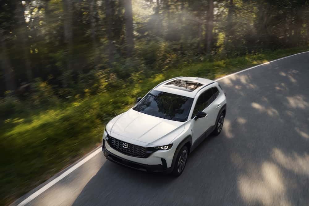 2025 Mazda CX-50 Hybrid driving on a tree-lined road