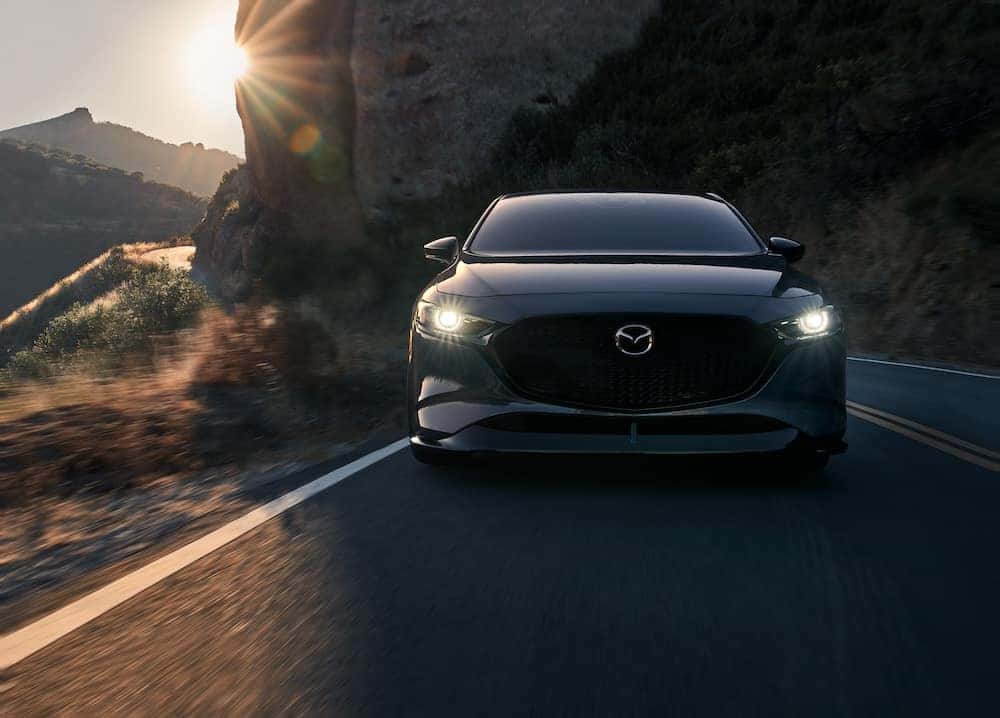 Mazda3 sedan driving with headlights on