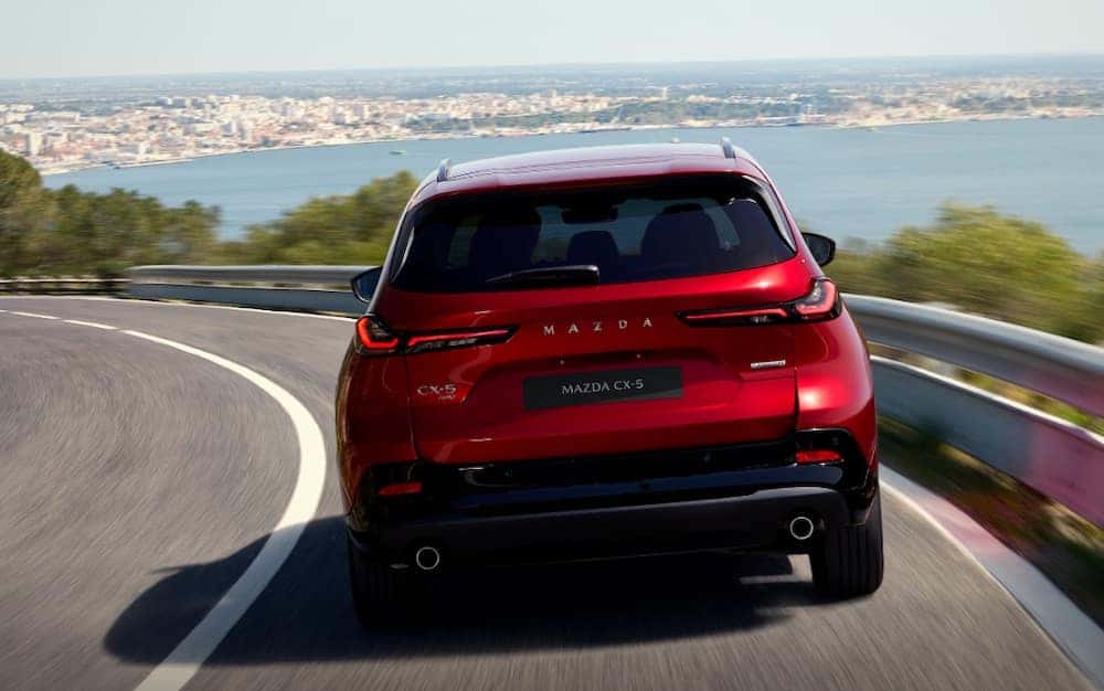 Red 2026 Mazda CX-5 rear view of exterior as it drives down a highway